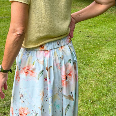 Fast stof med sommerblomster på lyseblå bund