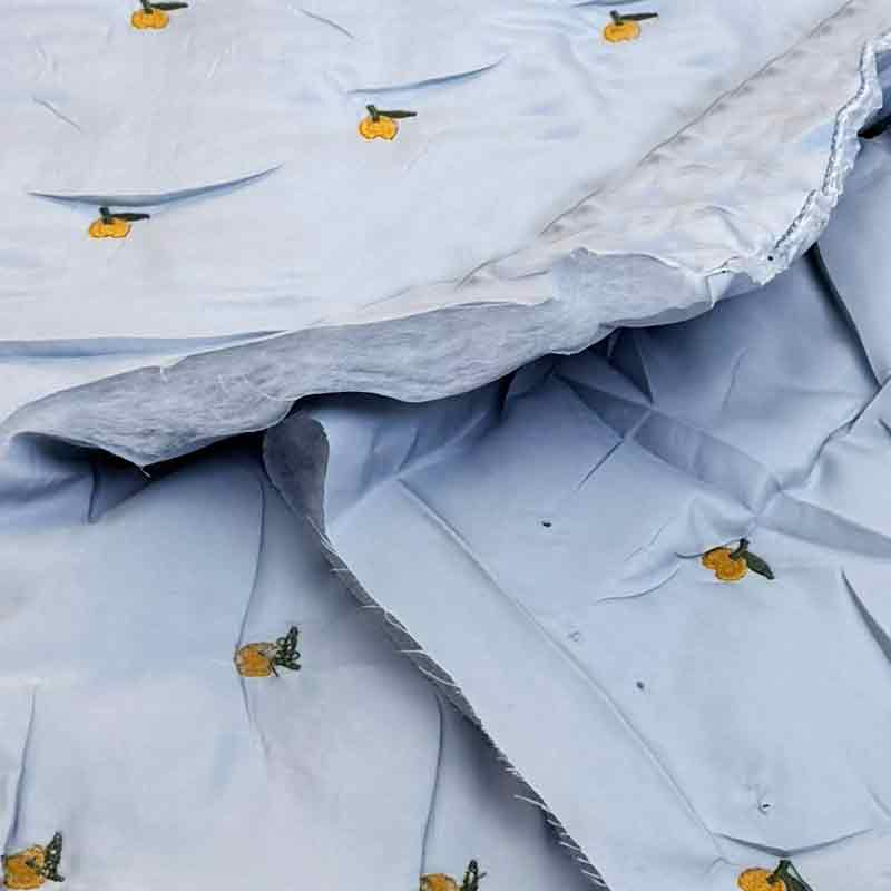 Lyseblå quilt med broderet frugt