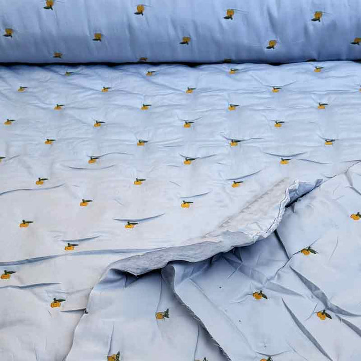 Lyseblå quilt med broderet frugt